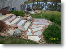 natural stone steps with flag stone steppers leading to a brick paver patio